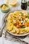 Pasta Mafaldine Napoletane with baked pumpkin, feta cheese and seasoning herbs in ceramic plate on white wooden background.