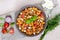 Pasta Radiatori with chicken, mushrooms, cherry tomatoes, feta cheese and tomato sauce on a light background.