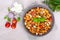 Pasta Radiatori with chicken, mushrooms, cherry tomatoes, feta cheese and tomato sauce on a light background.