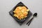 Pasta reginette with seafood, shrimps, mussels black plate on gray stone table, close up. Traditional dish in Italian restaurant