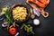 Pasta, salmon fish and ingredients for cooking on black background, top view. Italian food