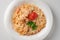 Pasta with salmon in a white plate is decorated with tomatoes and herbs in close-up