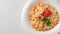 Pasta with salmon in a white plate is decorated with tomatoes and herbs near the copy space