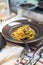 Pasta with seafoods at the brown plate with fork and cutlery out of focus