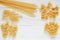 Pasta, set of raw farfalle, spaghetti, pipe, maccheroni, penne, cresta,  on white wooden board background, top view, space to copy