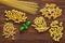 Pasta, set of raw farfalle, spaghetti, pipe rigatoni, maccheroni, penne rigate, cresta di gallo, basil leaf,  on wooden plank dark