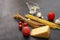 Pasta, several tomatoes, garlic, piece of cheese, gravy boat with oil on black background