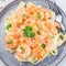 Pasta with shrimps in creamy parmesan cheese and garlic sauce garnished with parsley, fettucini alfredo, top view, square format,