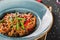 Pasta spaghetti with sauce, stew vegetables and seeds in plate on dark stone table.Vegetarian noodles, Italian food