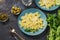 The pasta is sprinkled with cheese served on blue plates with arugula, olives and pickled capers.