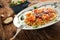 Pasta with tomato sauce and shrimps and fresh green salad on a wooden rustic table