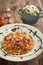 Pasta with tomato sauce and shrimps and fresh green salad on a wooden rustic table