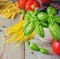 Pasta, tomatoes, and basil on wooden background