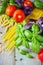 Pasta, tomatoes, and basil on wooden background