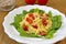 Pasta with tomatoes, sunflower seeds and salad served on the wooden table