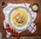 Pasta with turkey in cream sauce, cheese, cherry tomatoes on a branch, on a white plate on a napkin on wooden rustic background to