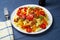 Pasta with vegetables. Fettuccine with grilled meat, carrots, bell peppers, dill tomatoes on a blue wooden background.