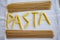 Pasta word written with pieces of pennette pasta
