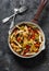 Pasta, zucchini, mushrooms, sweet paprika vegetable stewed tomato sauce in a pan on a dark background, top view. Vegetarian food