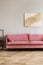 Pastel abstract painting on beige wall behind velvet pink settee in simple living room