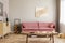 Pastel abstract painting on beige wall behind velvet pink settee in simple living room