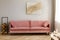 Pastel abstract painting on beige wall behind velvet pink settee in simple living room