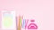 Pastel colored back to school supplies, notebook, crayons, rulers, scissors, eraser appear on bottom of pastel pink background - S