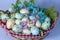 Pastel colour easter eggs with flowers in basket close up