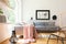 Pastel pink blanket thrown on corner couch standing in white living room interior with simple poster, lantern, decor and big windo