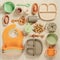 Pastel silicone set of tableware, cutlery, bibs, accessories and wooden toys for children on white cloth background.