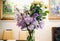 Pastel summer bouquet in the glass vase standing on the table in the restaurant. Lilac iris flowers and white roses in rustic