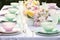 a pastel table setup with plates, napkins, and cups