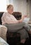 Pastimes. An elderly woman in glasses enjoys her hobby sitting in a armchair and reading letters on the background of