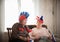 Pastimes. An elderly women supports sport team with flags sitting against TV on the backgrond of window