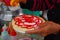 PASTO, COLOMBIA - JULY 3, 2016: woman preparing a dessert with some wafers, strawberry syrup and coconut