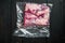 Pastrami meat packed in vacuum plastic bags, on black wooden table background, top view flat lay , with copyspace  and space for