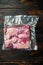 Pastrami meat packed in vacuum plastic bags, on old dark  wooden table background, top view flat lay