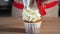 Pastry chef decorates muffin in paper cups white cream with pastry bag.