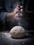 pastry chef hand sprinkling white flour over Raw Dough on kitchen table.