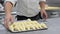 Pastry chef rolling croissant dough, and putting in a baking tray in the pastry shop.