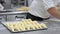 Pastry Chef rolling croissant dough, and putting in a baking tray in the pastry shop.