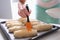Pastry chef smearing egg yolk on raw bun with silicone brush closeup