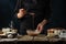 Pastry chef testing the dough by spoon on table with ingredients for cooking on dark blue background. Backstage of preparing sweet