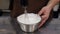A pastry chef whipping milk cream with a blender in a professional kitchen.