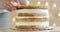 Pastry chef woman is putting sponge cake on cream making cake, hands closeup.