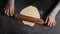 A pastry chef woman rolls out raw yeast dough for buns or pizza.