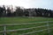 Pasture land surrounded with a wooden fence. Inside there is fresh green grass for the cows.