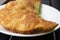 pasty with beef and pork on a white plate, decorated with vegetables and herbs on a wooden table