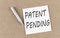 PATENT PENDING text on sticky note on cork board with pencil