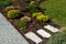 Path through flowerbed using stepping stones made of marl sandstone bright colors blooming in flowerbed perennials yellow lawn bar